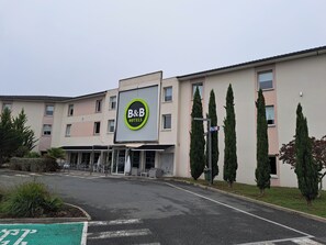 Un hotel tipo B&B con fachada moderna, estacionamiento y cielo despejado.