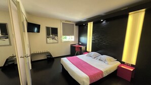 Una habitación de hotel moderna con cama, mesitas de noche, escritorio y televisor.