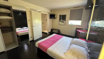 A hotel room with a bed, a desk, a TV, and a wardrobe.