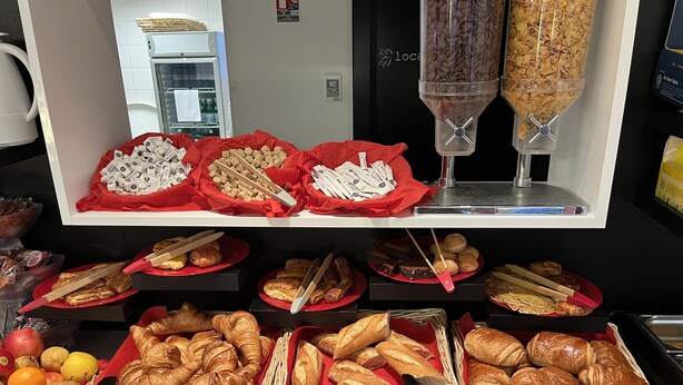 Un bufé con diversas opciones de comida, entre ellas pasteles, frutas y salsas.