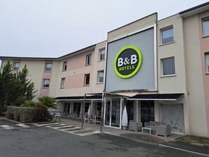 Un hotel B&B con una fachada moderna, zona de estar exterior y entrada despejada.