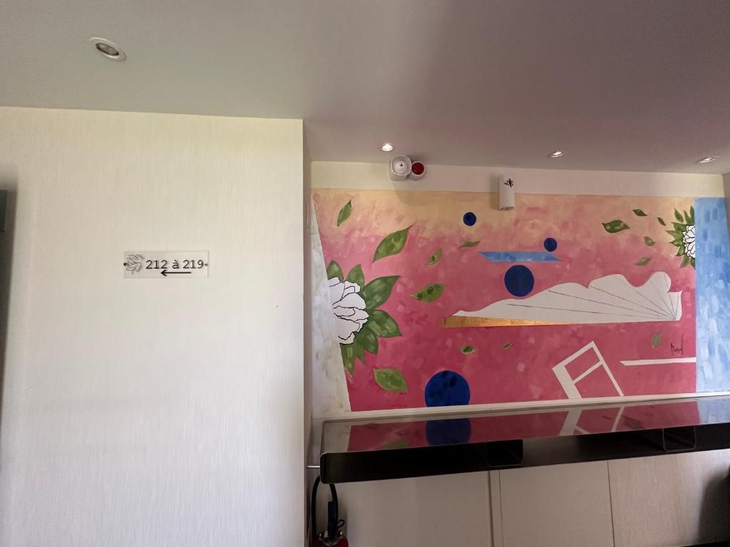 A room with a wall-mounted artwork, a white door with a number sign, and a black counter.