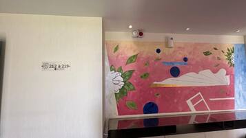 Habitación con una obra de arte colgada en la pared, una puerta blanca con un letrero de número y un mostrador negro.