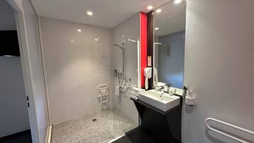 A modern bathroom with a shower, a sink, and a mirror.