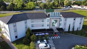 Un hotel con un patio central, mobiliario exterior y zona de estacionamiento.