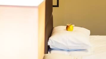 Una camera d'albergo con un letto, cuscini e una lampada.