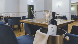 Ein Essbereich mit einem Tisch für zwei Personen, einer Weinschorle in einem Kübel und einer Kerze auf dem Tisch.