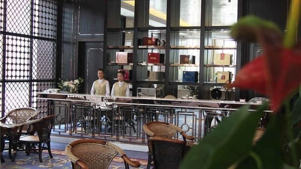 A bar area with wicker chairs and a bar counter, with a decorative screen and shelves in the background. - GreenTree Huainan Tianjiaan Square Guangchang road Hotel (Huainan)