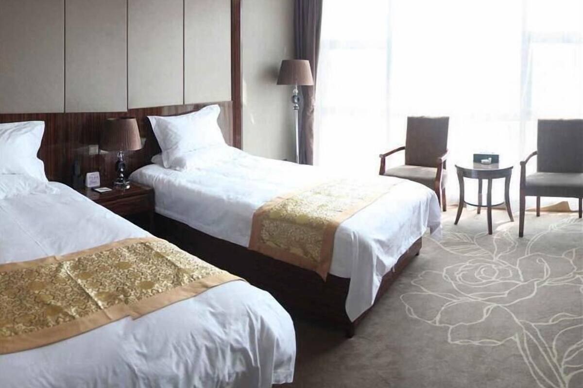 Ein Hotelzimmer mit zwei Betten, einem Schreibtisch, einem Stuhl und einer Lampe.