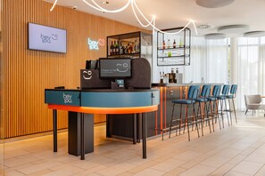 A modern bar area with a check-in counter, bar stools, and a display of bottles.