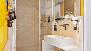 Une salle de bain moderne avec une douche à parois de verre, un lavabo blanc et un miroir.