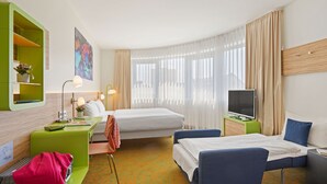 Une chambre d’hôtel avec un lit, un bureau avec un ordinateur, une télévision et une chaise.