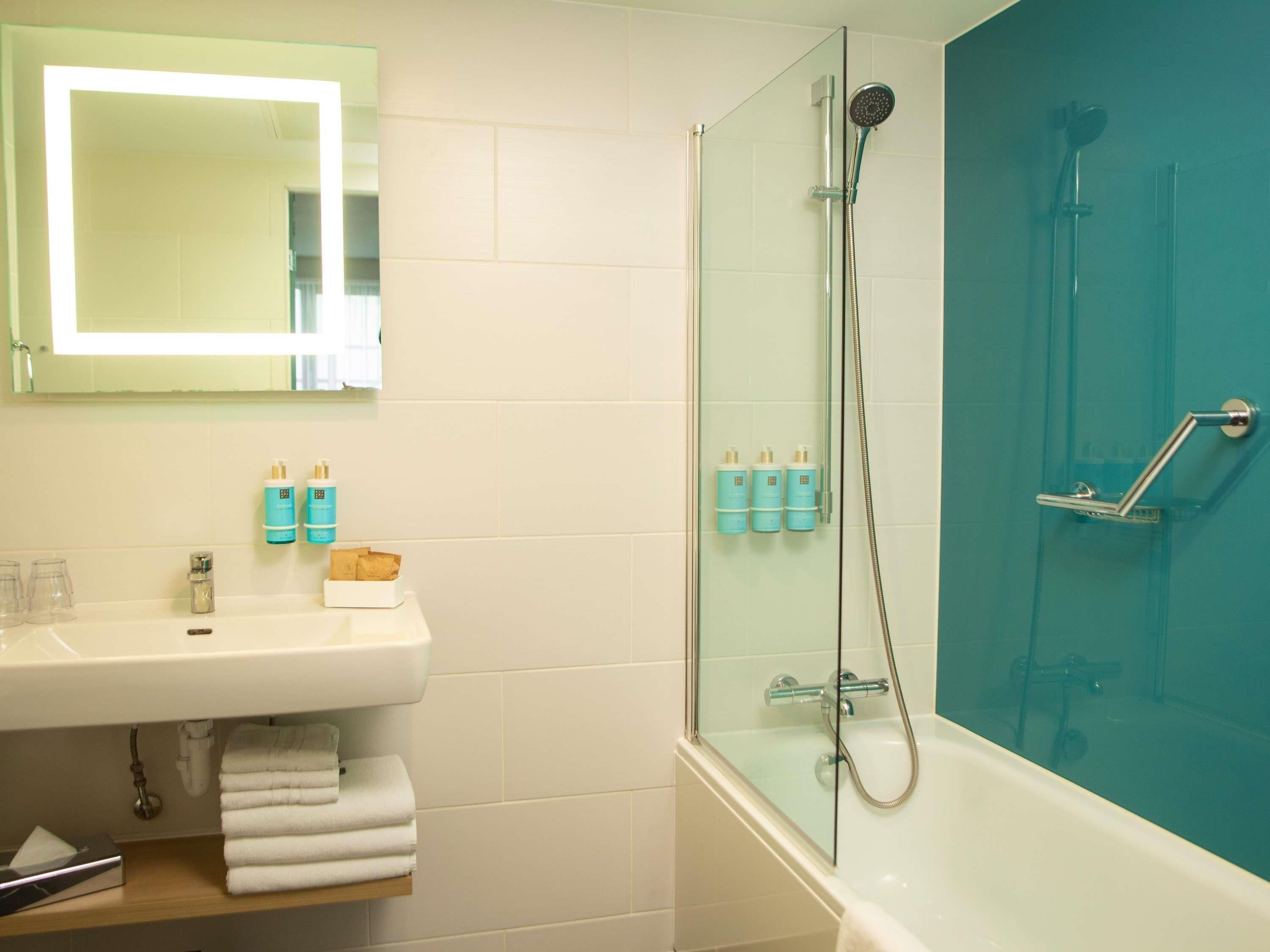 A bathroom with a glass-enclosed shower, a white sink, and a mirror above it.