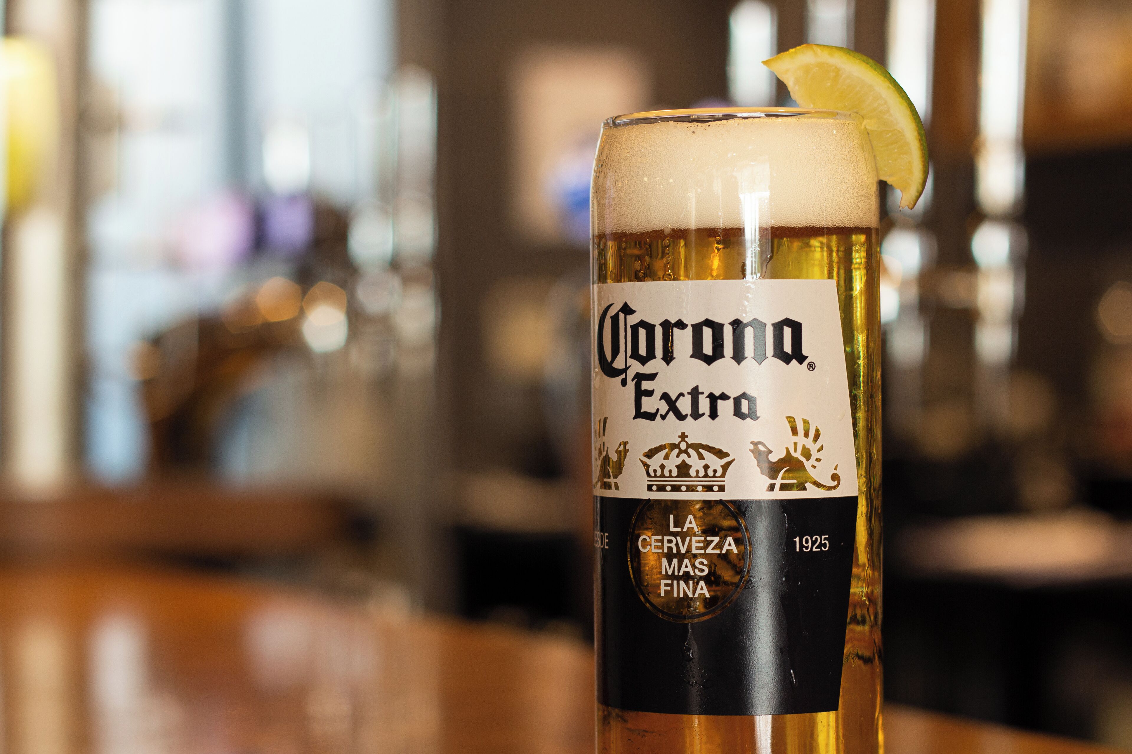 A glass of Corona Extra beer with a lime wedge on the rim.
