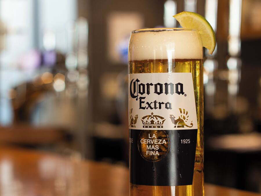 Una cerveza Corona Extra en un vaso, con una rodaja de limón en el borde.