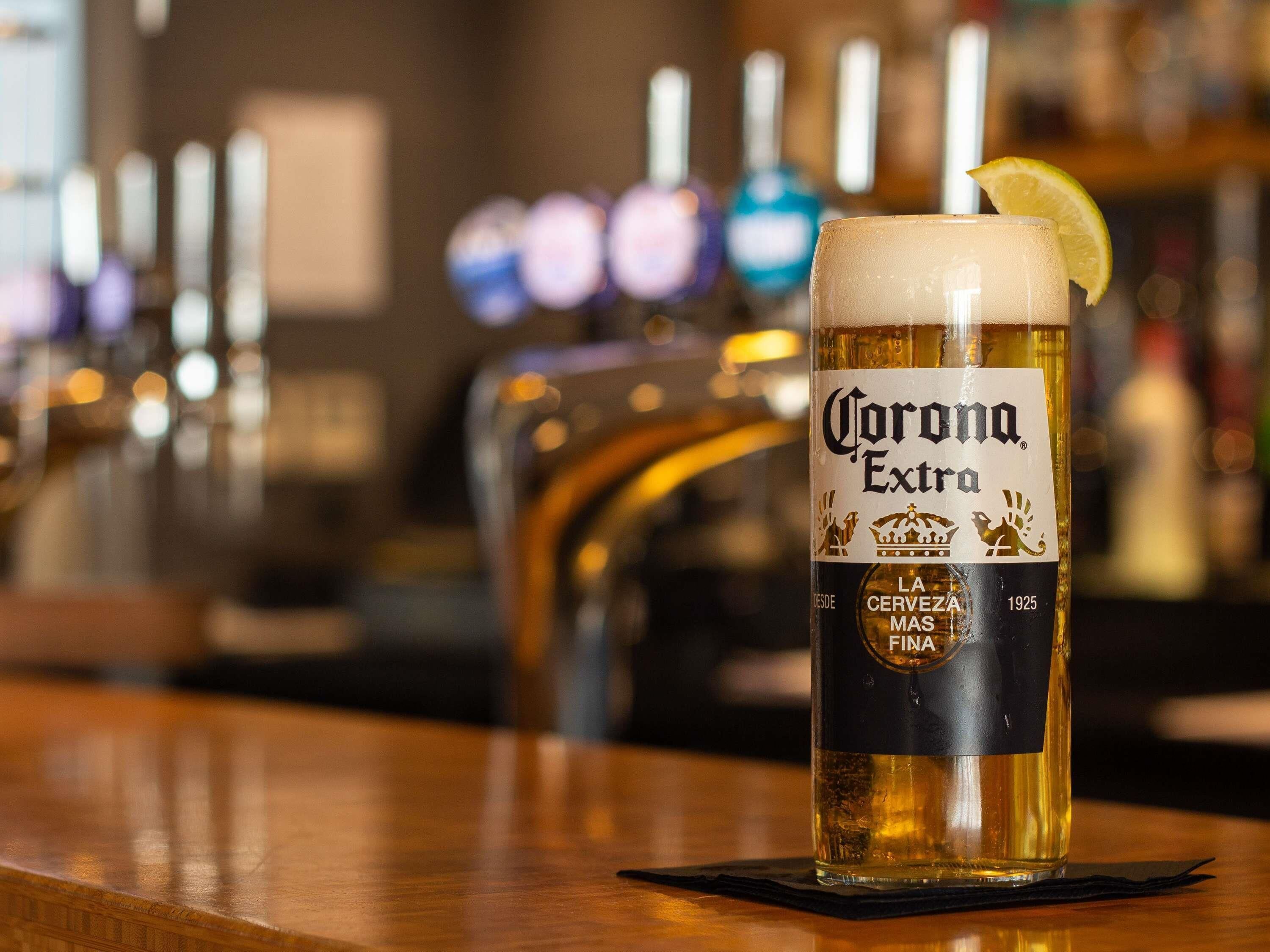 Un bicchiere di birra Corona Extra con una fetta di limone su un bancone da bar.