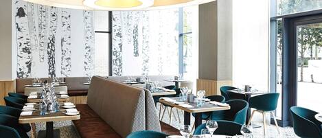 A restaurant with round tables, booths, and a large circular light fixture.