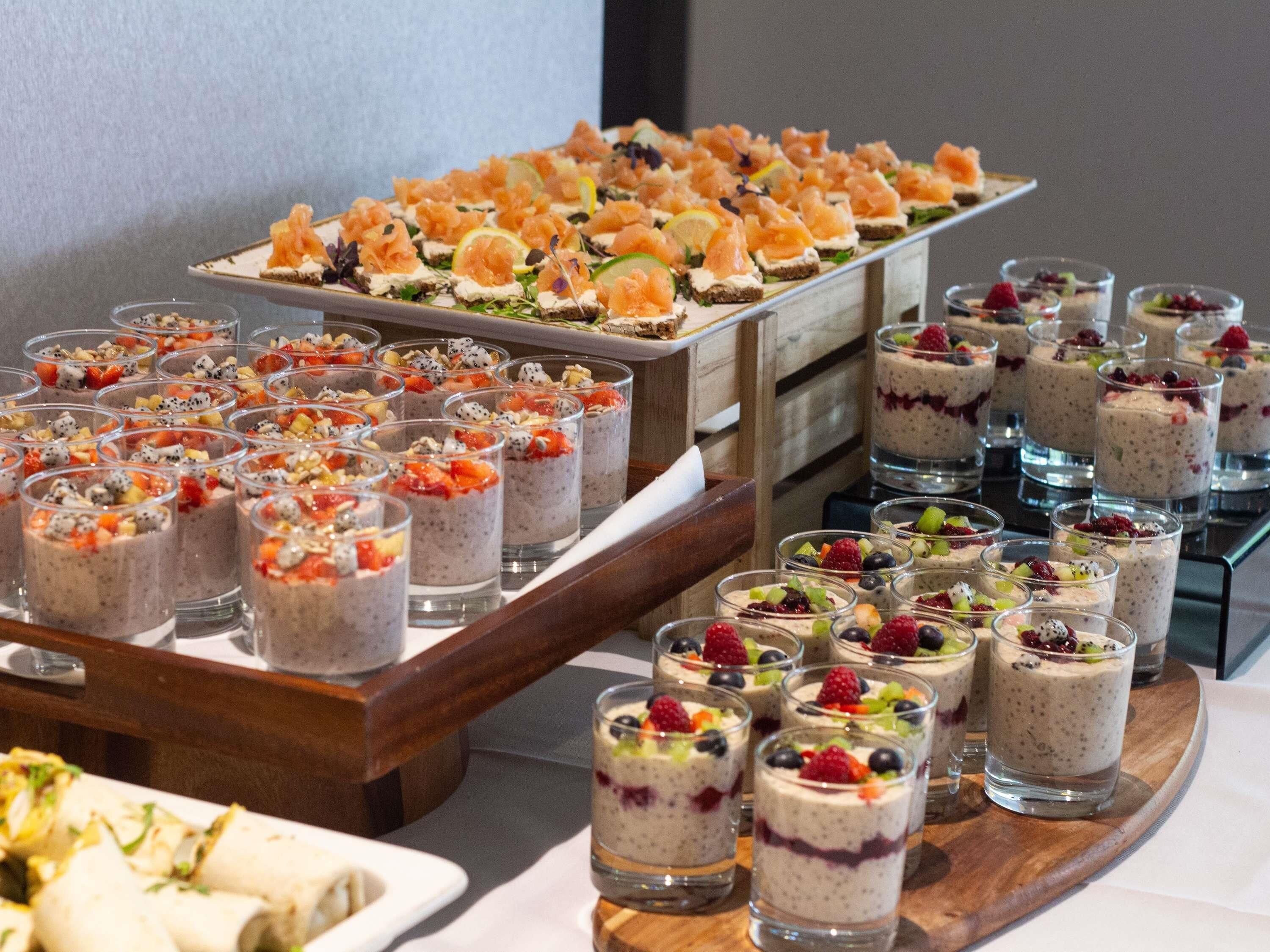 A buffet with various food options including sushi, fruit parfaits, and other desserts.