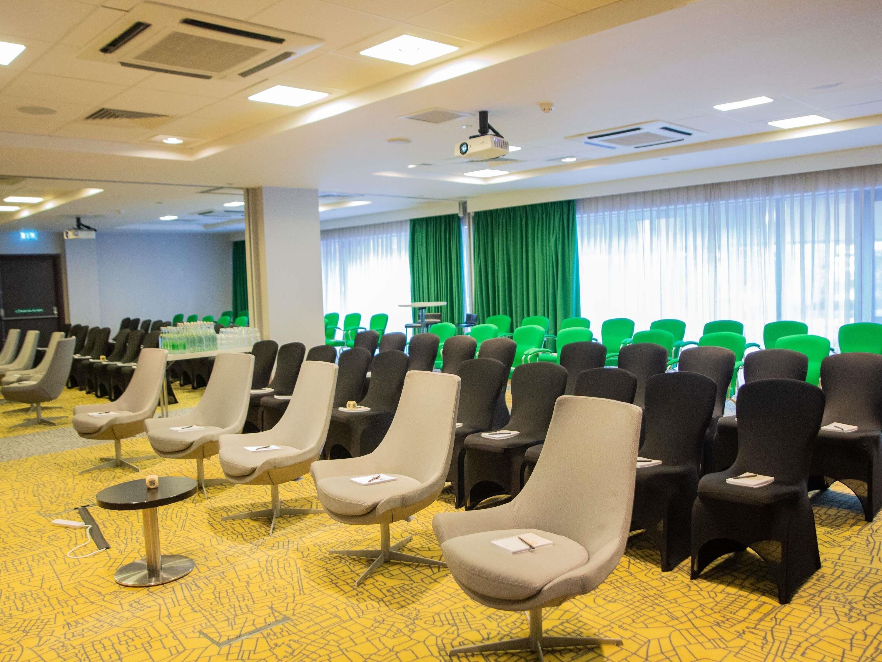 A conference room with rows of chairs, a projector, and a table with water bottles.