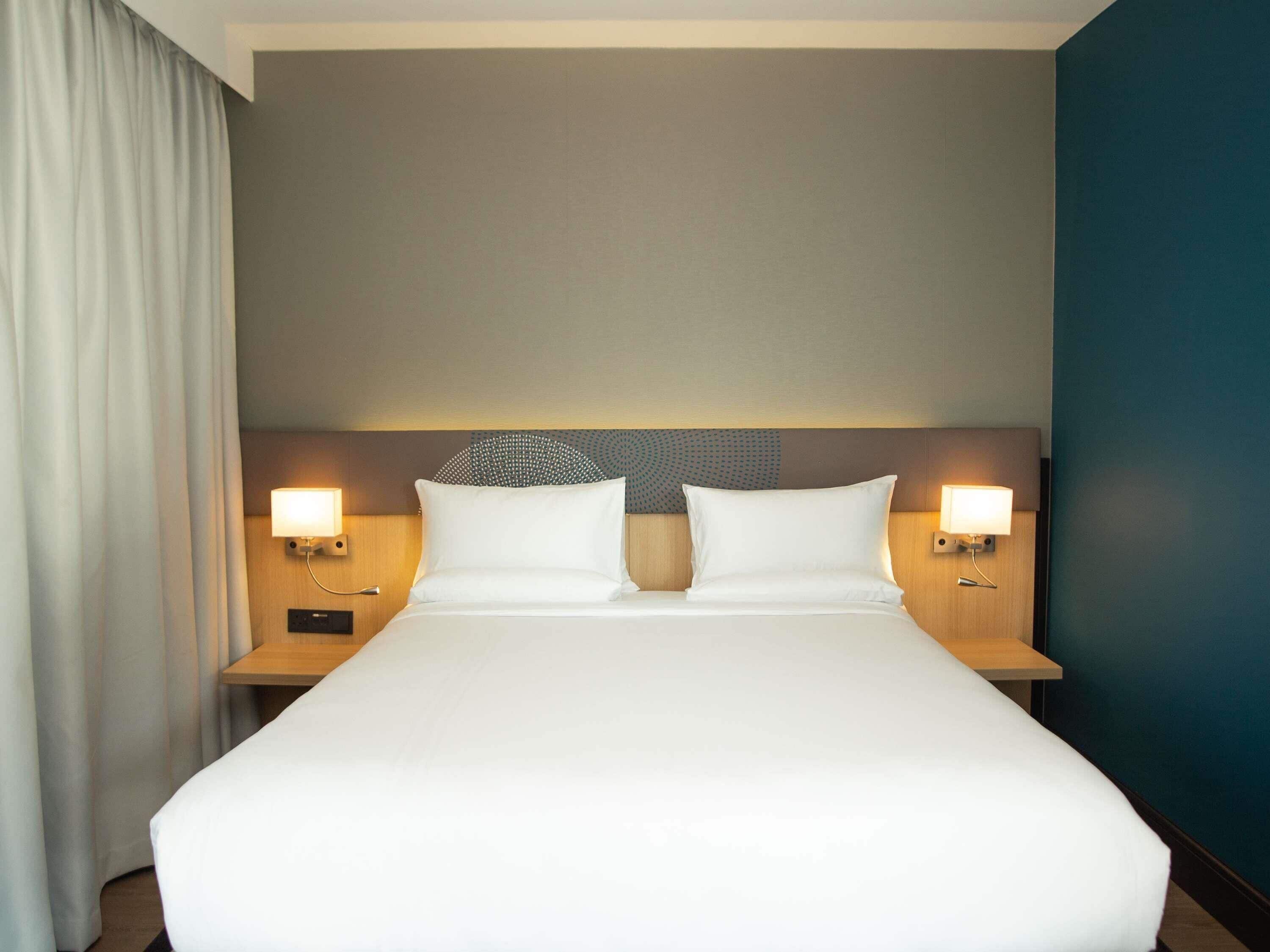 A hotel room with a large bed, two bedside tables, and a headboard with a decorative pattern.
