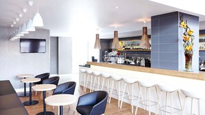 Un espace bar moderne offrant de nombreuses options de sièges, notamment des tabourets de bar et des tables rondes, ainsi qu’un comptoir de bar avec un présentoir à vin.