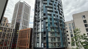 Un immeuble moderne de grande hauteur, doté de nombreux balcons, de grandes fenêtres et d’une façade combinant verre et métal.
