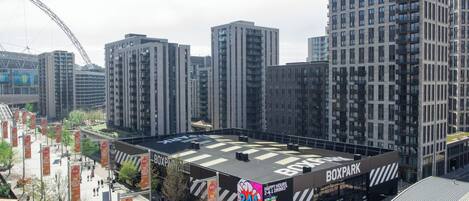 A modern building with a prominent 'Boxpark' sign, surrounded by high-rise buildings and a large arch structure in the background.