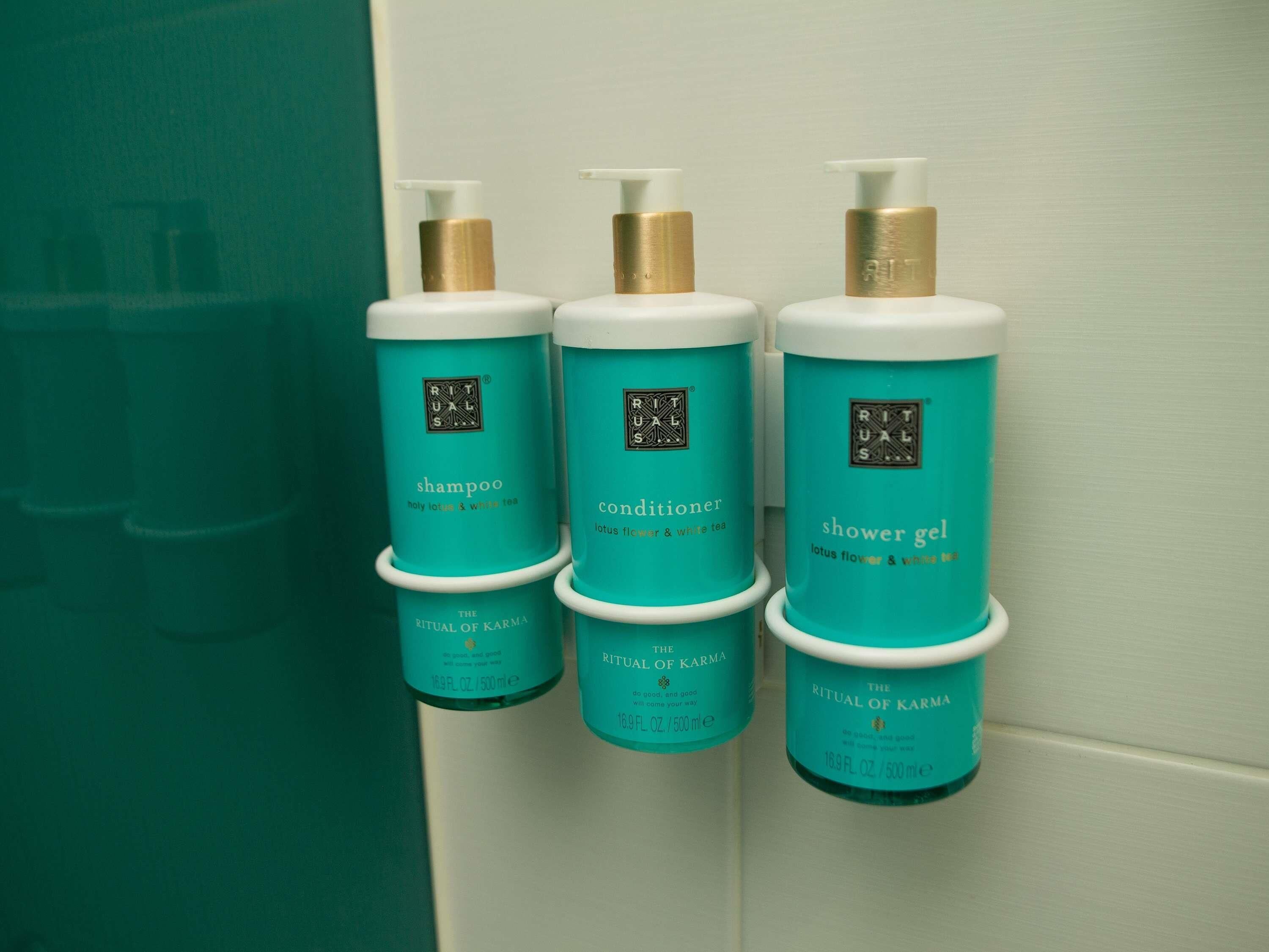 Three bottles of 'RITUAL OF KARMA' products: shampoo, conditioner, and shower gel, each with a teal label and gold cap.