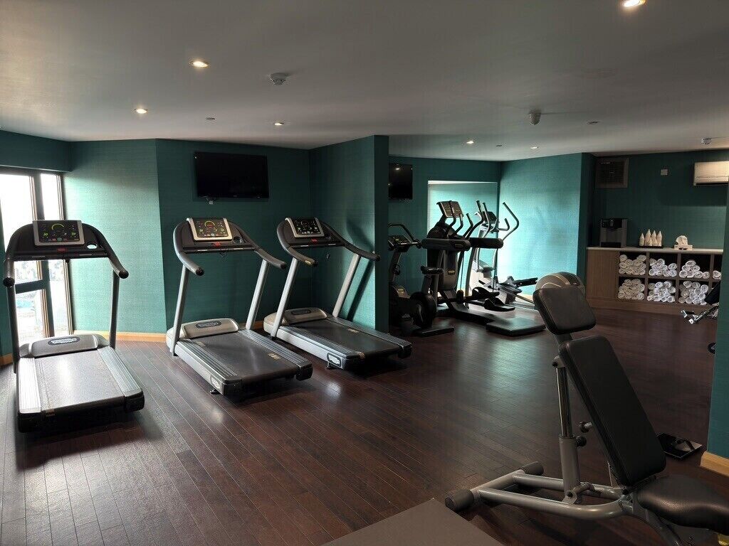 Un gimnasio con cintas de correr, una bicicleta estática y un banco para pesas.