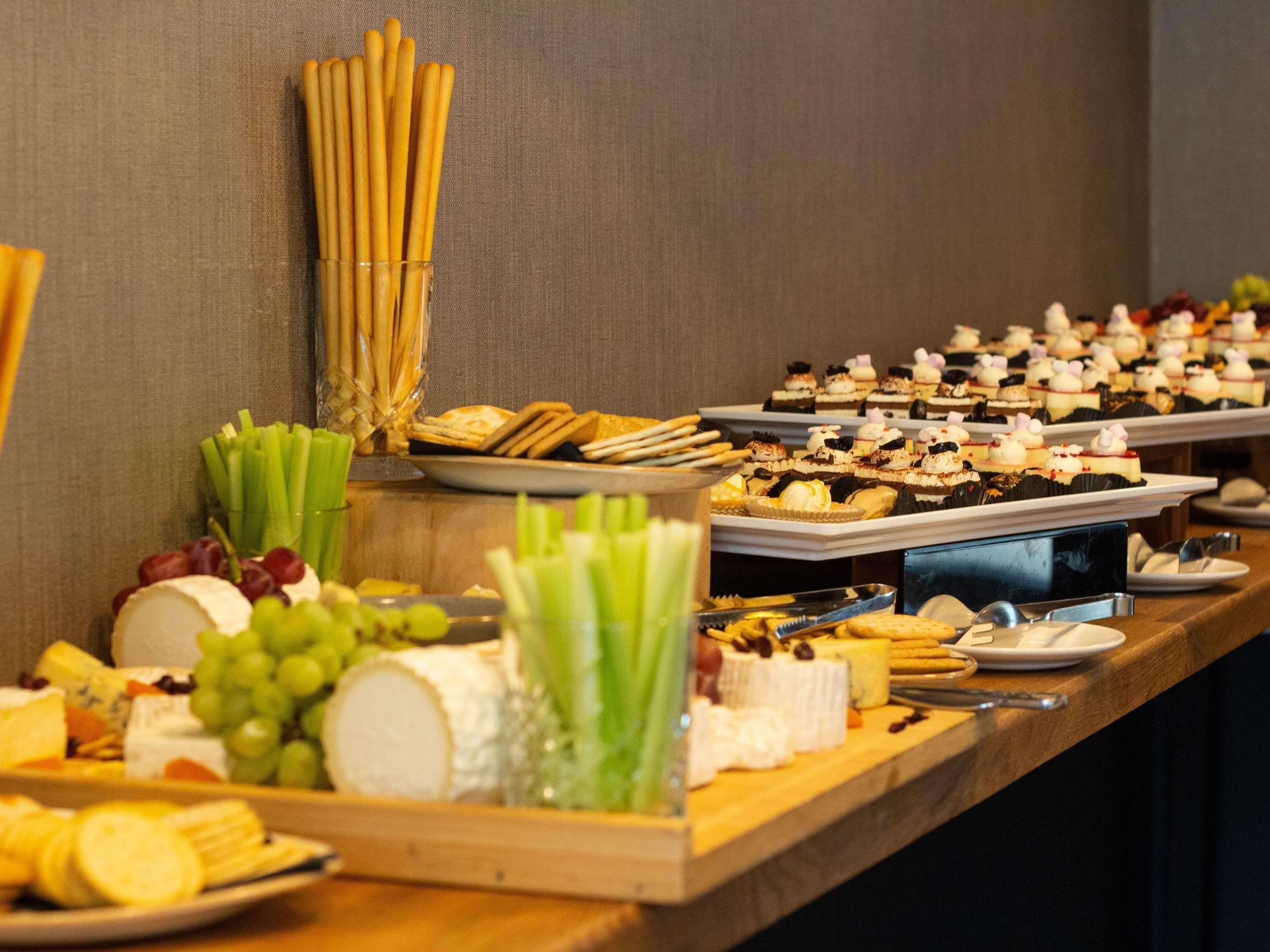 A buffet with various cheeses, fruits, and pastries.