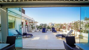 An outdoor patio with lounge chairs and a table, surrounded by potted plants and a glass door leading to a building. - Hotel Adria (Bari)
