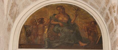 Un fresco dentro de un nicho arqueado, con una figura central sosteniendo un báculo y rodeada de figuras más pequeñas.