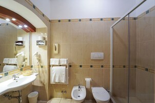Un baño con lavamanos, bidé, inodoro y ducha con mampara de vidrio.