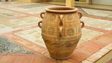 A large terracotta pot in a courtyard with a tiled floor and yellow walls.