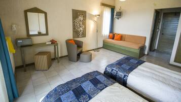 A hotel room with two beds, a sofa, a desk with a chair, a lamp, and a television.