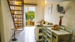 A cozy room with a dining table, chairs, a sofa, a TV, and a bookshelf. - Lycasti Maisonettes (Platanias)