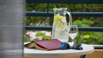 A table with a pitcher of iced tea, a glass of water, a book, and a pair of sunglasses.
