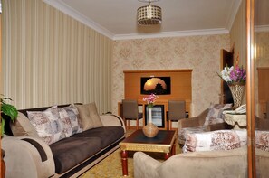 A living room with a sofa, armchairs, a coffee table, and a fireplace. - Alfa Hotel (Istanbul)