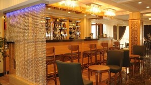 A bar area with a decorative wall, wooden chairs, and a bar counter with bottles. - Alfa Hotel (Istanbul)