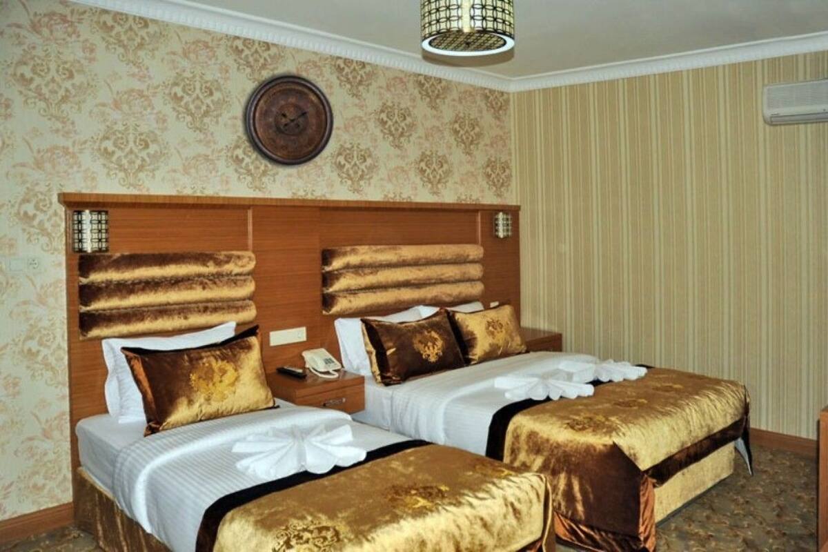 A hotel room with two beds, a wooden headboard, a clock, and a patterned wallpaper.