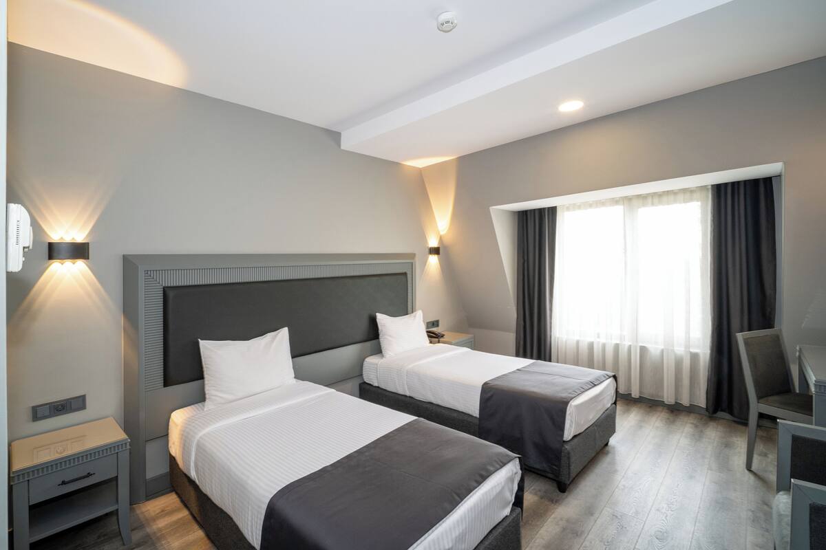 Ein Hotelzimmer mit zwei Betten, einem Schreibtisch und einem Sessel.