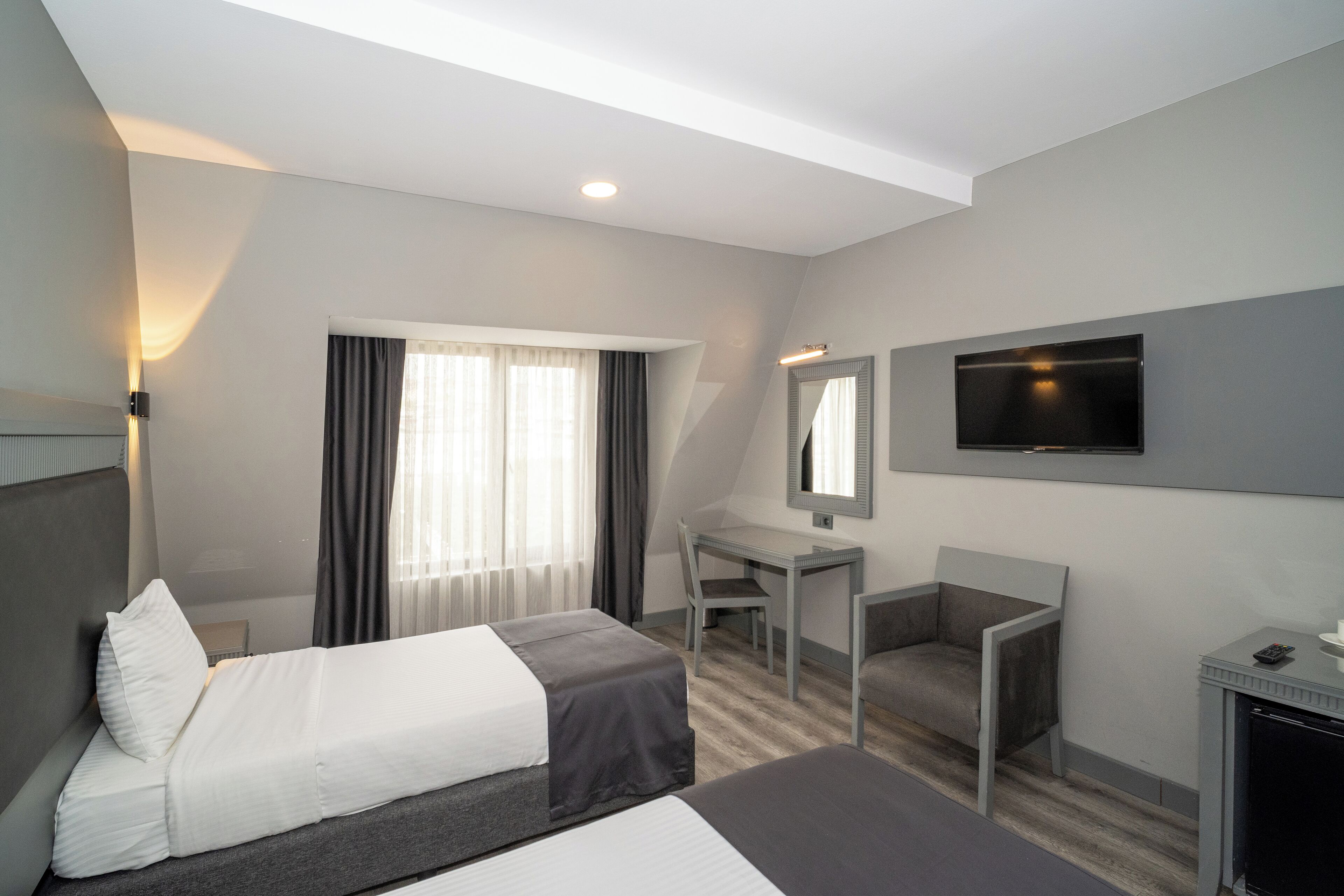 A hotel room with a bed, desk, chair, TV, and fireplace.