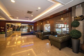 Un hall con sofás de cuero, un mostrador de recepción y un letrero que indica un restaurante.