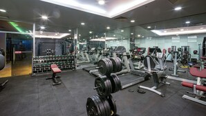 Una palestra moderna con diverse attrezzature per l'allenamento, tra cui manubri, tapis roulant e macchinari per pesi.