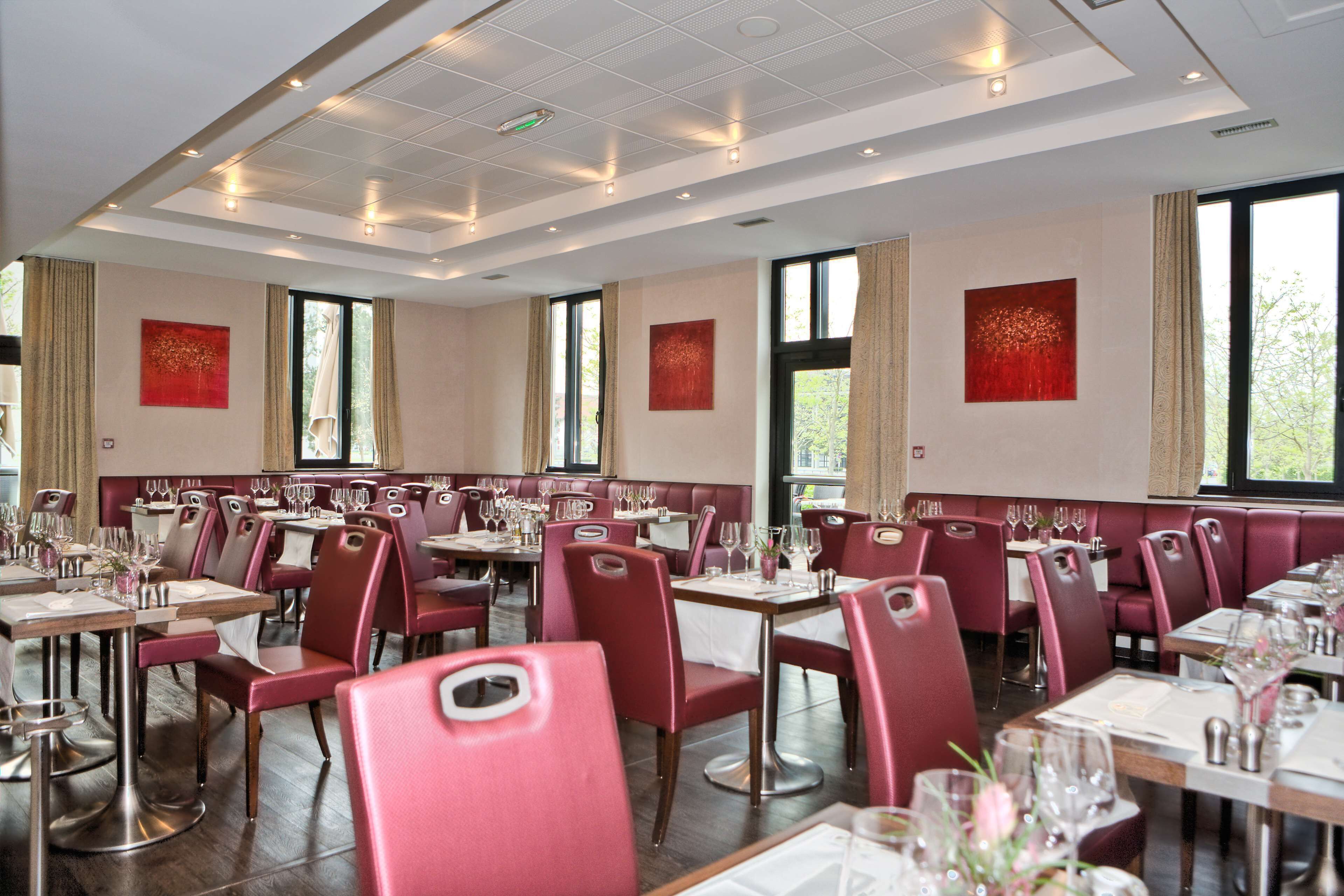 A restaurant with red upholstered booths and tables set for dining.