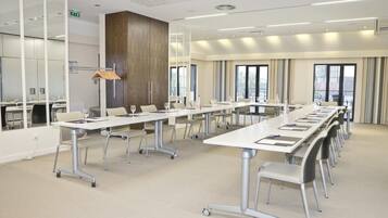 A modern conference room with a long table, chairs, and a large window.