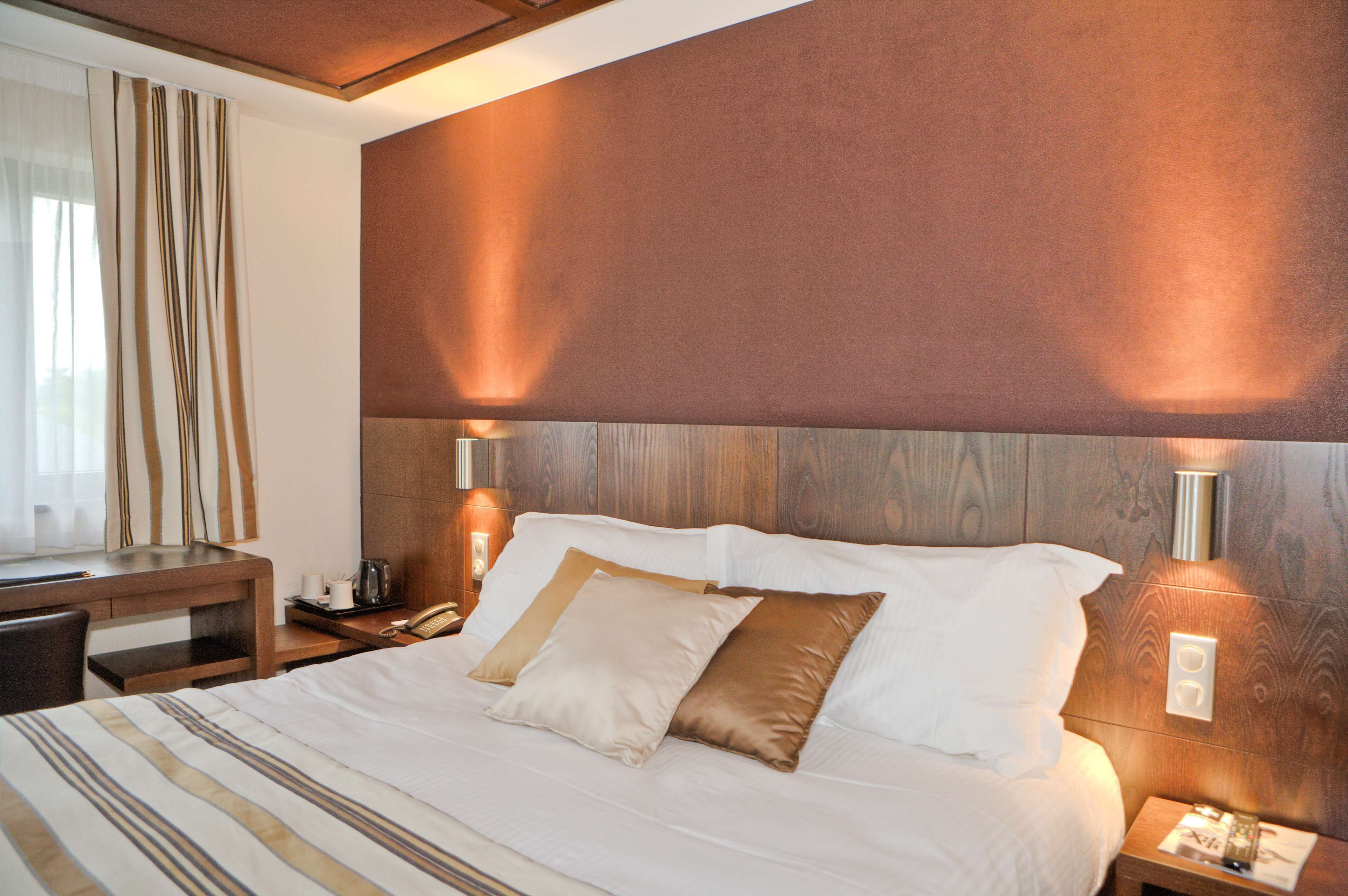 A hotel room with a large bed, bedside lamps, a desk, and a chair.