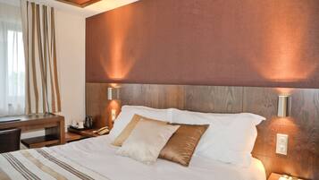 A hotel room with a large bed, bedside lamps, a desk, and a chair.