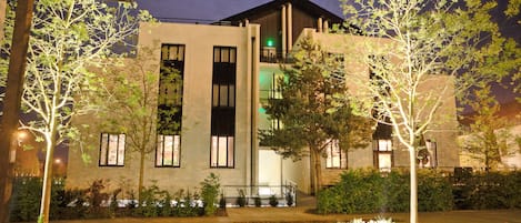 Un edificio moderno con tejado plano, amplias ventanas y una entrada bien iluminada.