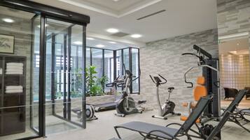 Une salle de sport moderne, dotée d’équipements d’exercice, de murs en verre et offrant une vue sur l’extérieur.